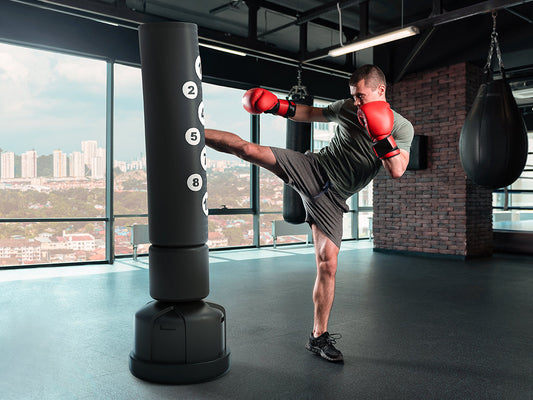 Mann trainiert Kickboxen zuhause an einem freistehenden Boxsack mit nummerierten Trefferzonen