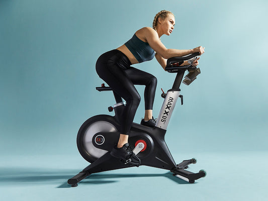 Sportliche Frau trainiert konzentriert auf einem MAXXUS SX3 Indoor Cycling Bike im Home Gym